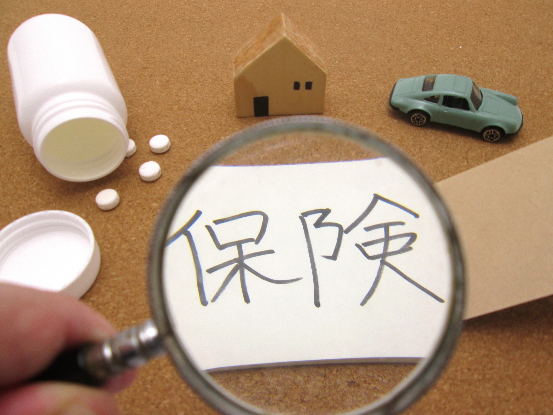 虫眼鏡と保険の文字が書かれた紙