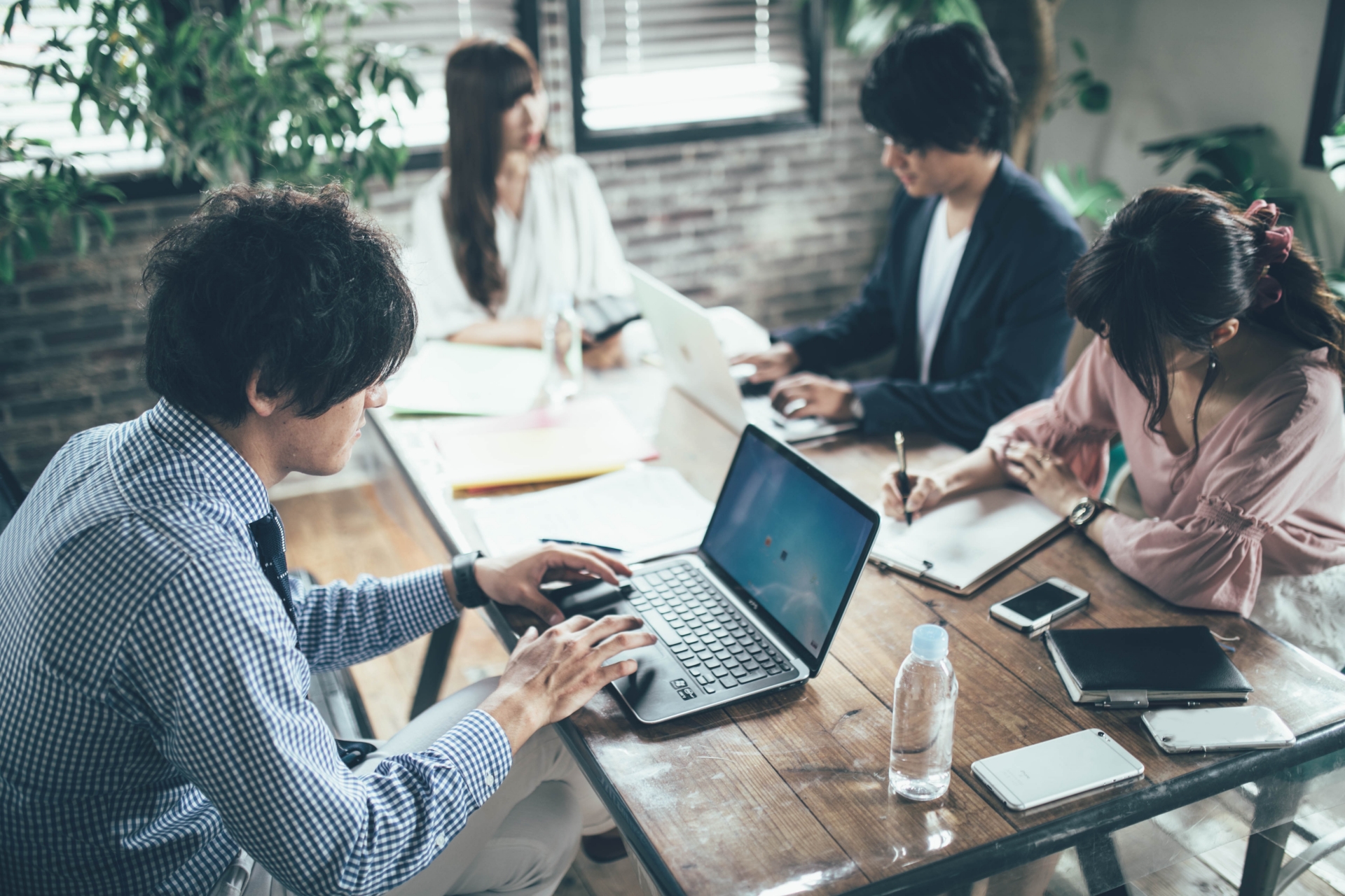 机の上で男女4人がパソコンで作業をしている