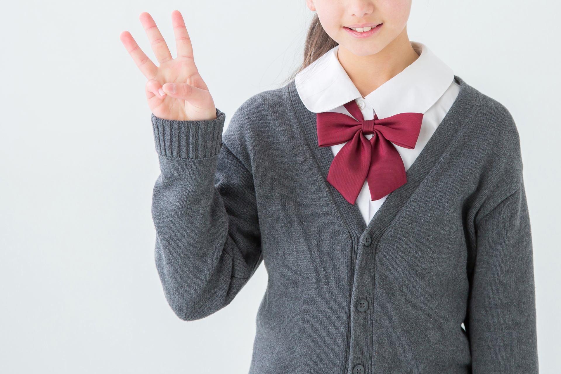 女子高生が3本指をあげている