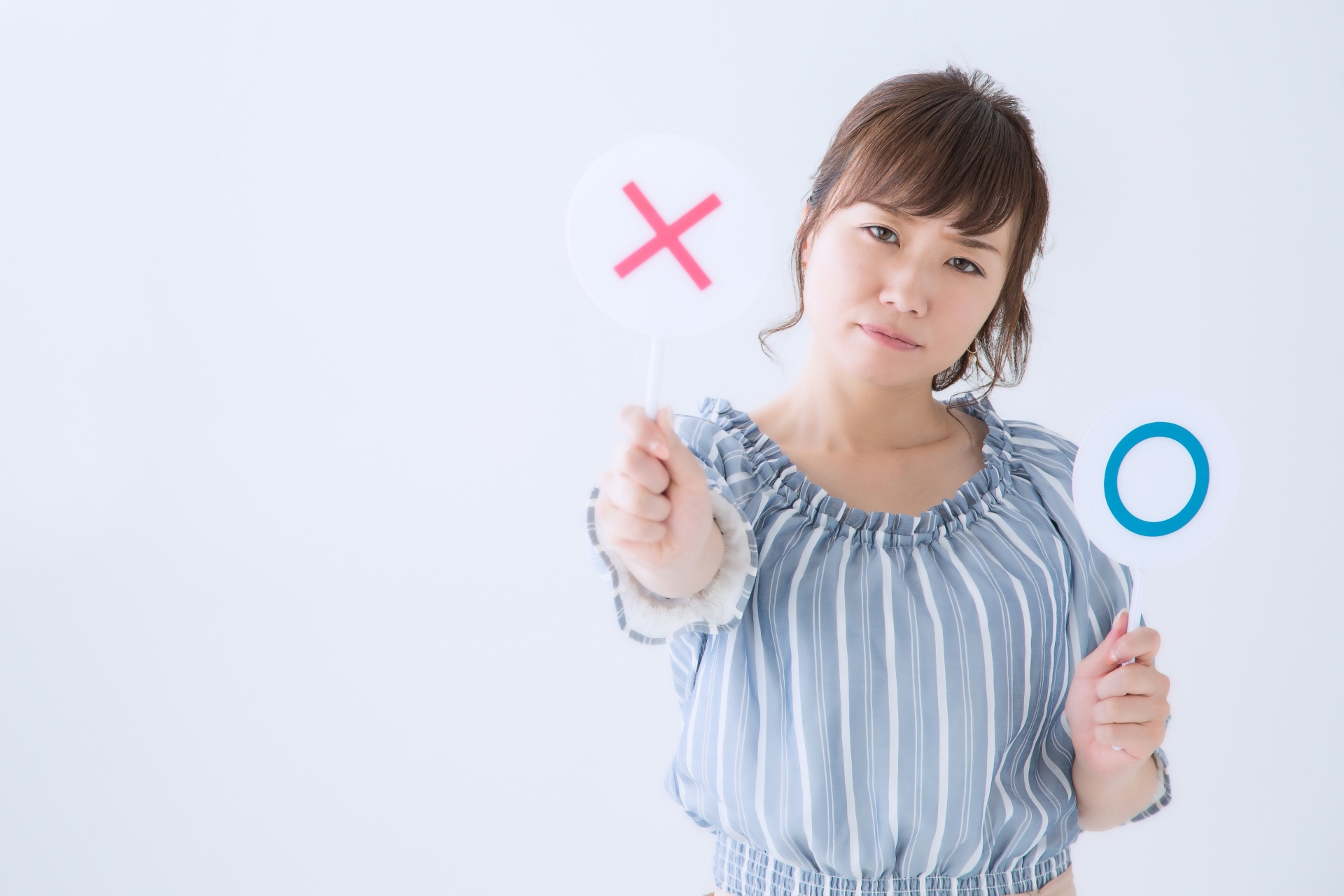 女性が〇×の札を持っており、×を前に出している