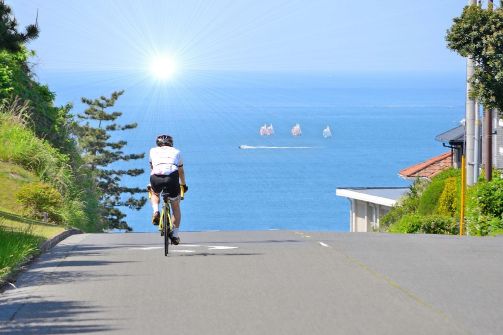 綺麗な海の見える道をロードバイクで走る男性